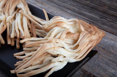 Örülmüş peynir at kuyruğu, baharatlı otlar roka ve maydanoz, ahşap arka planda, yakın plan. Yemekler için geleneksel tuzlu tel peyniri.