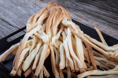 Örülmüş peynir at kuyruğu, baharatlı otlar roka ve maydanoz, ahşap arka planda, yakın plan. Yemekler için geleneksel tuzlu tel peyniri.