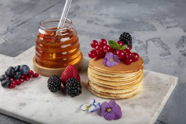 Krepler. Sağlıklı yaz kahvaltısı, ev yapımı klasik Amerikan krepleri taze böğürtlen ve bal ile, sabah üstü gri taşlı arka plan fotokopi alanı