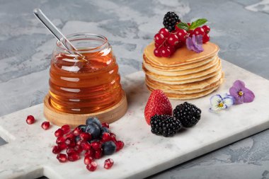Krepler. Sağlıklı yaz kahvaltısı, ev yapımı klasik Amerikan krepleri taze böğürtlen ve bal ile, sabah üstü gri taşlı arka plan fotokopi alanı