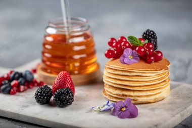 Krepler. Sağlıklı yaz kahvaltısı, ev yapımı klasik Amerikan krepleri taze böğürtlen ve bal ile, sabah üstü gri taşlı arka plan fotokopi alanı