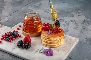 Krepler. Sağlıklı yaz kahvaltısı, ev yapımı klasik Amerikan krepleri taze böğürtlen ve bal ile, sabah üstü gri taşlı arka plan fotokopi alanı