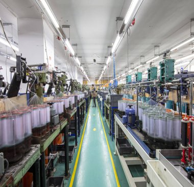Bir iplik imalat şirketinde makine ve ekipman. Tekstil endüstrisi. Tekstil fabrikasında dönen bir makine. Kumaş fabrikasında iplik çevirme işlemi.
