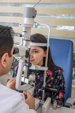 Erkek doktor oftalmolojist modern klinikte genç ve güzel bir kadının gözlerini kontrol ediyor. Göz hekimliği kliniğinde doktor ve hasta..