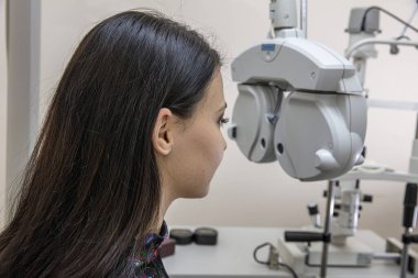 Görme bozukluğu teşhisi konulmuş bir hasta, göz doktoru kabini. Optisyen bir kadının görme yeteneğini ölçüyor. Klinikteki göz doktorunu ziyaret eden genç bir kadın. Optometrist genç ve güzel bir kadının görüşünü kontrol ediyor..