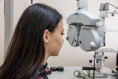Görme bozukluğu teşhisi konulmuş bir hasta, göz doktoru kabini. Optisyen bir kadının görme yeteneğini ölçüyor. Klinikteki göz doktorunu ziyaret eden genç bir kadın. Optometrist genç ve güzel bir kadının görüşünü kontrol ediyor..