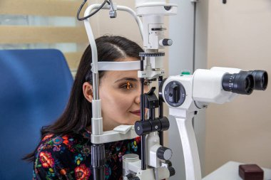 Görme bozukluğu teşhisi konulmuş bir hasta, göz doktoru kabini. Optisyen bir kadının görme yeteneğini ölçüyor. Klinikteki göz doktorunu ziyaret eden genç bir kadın. Optometrist genç ve güzel bir kadının görüşünü kontrol ediyor..
