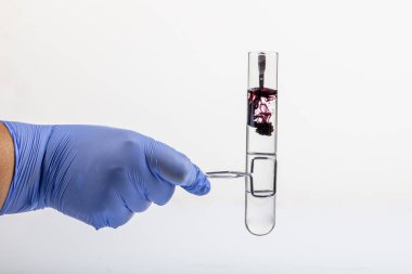 Siyah reaksiyonlu test tüpü ve yakın plan pipet. Elinde test tüpünde renkli sıvı var. Cam pipetten test tüpüne siyah sıvı damlası, beyaz üzerinde izole edilmiş. .