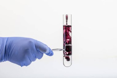 Siyah reaksiyonlu test tüpü ve yakın plan pipet. Elinde test tüpünde renkli sıvı var. Cam pipetten test tüpüne siyah sıvı damlası, beyaz üzerinde izole edilmiş. .