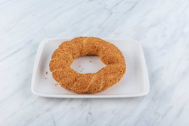 Simit ya da Yaşrek. Susamlı Türk simidi. Geleneksel Türk fırını ve sokak yemekleri. Mermer zemin üzerinde taze Türk simidi. 