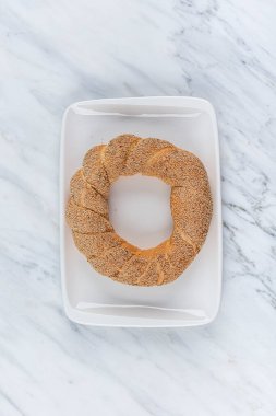 Simit ya da Yaşrek. Susamlı Türk simidi. Geleneksel Türk fırını ve sokak yemekleri. Mermer zemin üzerinde taze Türk simidi. 