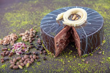 Beyaz ahşap arka planda dilimlenmiş şam fıstıklı pasta. Koyu çikolata kaplı ev yapımı çikolatalı kek ve fıstıklı fındık..