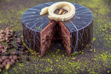 Beyaz ahşap arka planda dilimlenmiş şam fıstıklı pasta. Koyu çikolata kaplı ev yapımı çikolatalı kek ve fıstıklı fındık..