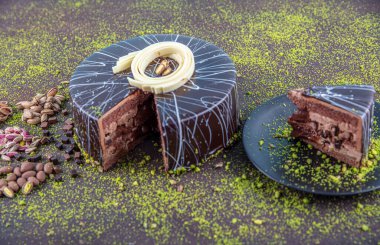 Beyaz ahşap arka planda dilimlenmiş şam fıstıklı pasta. Koyu çikolata kaplı ev yapımı çikolatalı kek ve fıstıklı fındık..