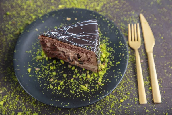 Pistachio cake sliced on white wooden background. Homemade Chocolate Cake with Dark Chocolate Glaze and Pistachios Nuts.