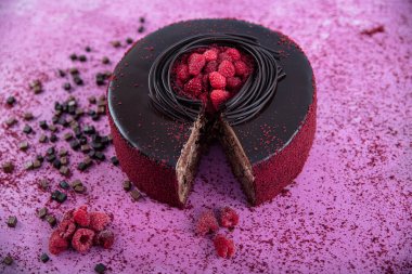 Çikolata genoise katmanlarından yapılmış ahududu pastası ahududu jölesiyle kaplanmış ve yabanmersini ve ahududu ile süslenmiş. Doğum günü pastası. Hediye keki..