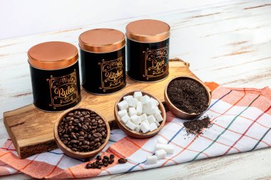 Set of 3 Storage Tins for housing teas, coffee and sugar. Set of three Storage Jars.Three pastel colorful kitchen storage jars for tea, sugar and coffee arranged in a row on wooden table.