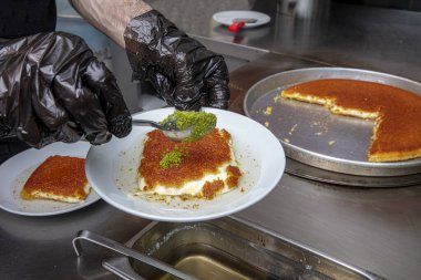 Sıcak servis edilen Türk tatlısı, kunefe, fıstık tozu ve peynir kadayif çok tatlıdır. Geleneksel Türk tatlısı. Şef mutfakta servis için Kunefe tatlısını hazırlıyor..