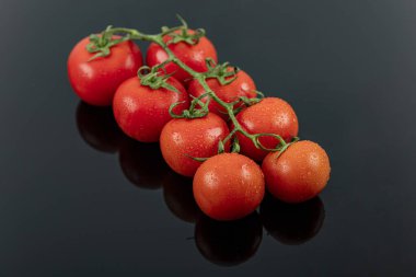 Güzel, taze, sarmaşık domatesleri (kiraz), bir damla su, çiğ, bütün ve yarım. Siyah desenli arka planda. Akdeniz diyetinin içeriği. Kopyalama alanı olan üst görünüm