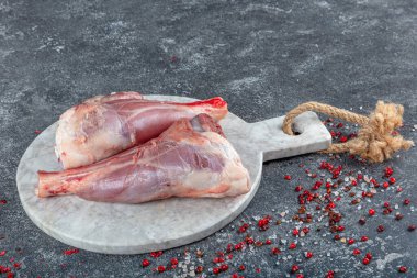 Genç kuzudan taze taze taze et. Çiğ kuzu bacağı mermer taştan arka planda otlarla.