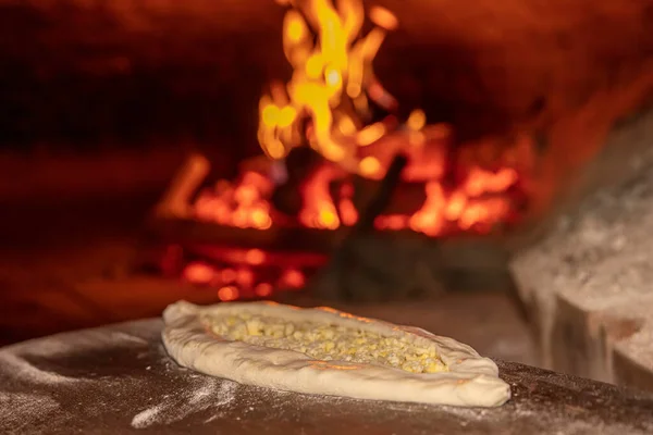 Turkish cuisine, pita bread in stone brick natural flame oven on wooden board, fresh hot baked loaf, copy space. Bakery or bakehouse concept image