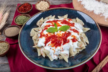 Mükemmel Türk Ravioli 'si ve tereyağında kızartılmış acı biber. Kırmızı biber, domates sosu, yoğurt ve naneli Türk mantı. Geleneksel Türk yemeği tabağı