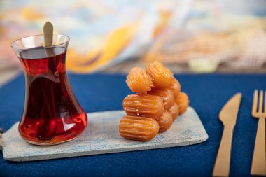 Geleneksel Türk tatlı tulumbası, çay ile servis edilen bir tabakta tuumba tatlisi. Tulumba (veya Bamiyeh), Osmanlı mutfağında popüler bir Türk tatlısıdır.