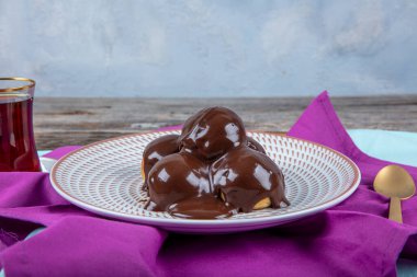 Çikolata ve tabakla nefis profiteroller. Krema ve çikolata kaplı lezzetli profiteroller. Ev yapımı profiterol choux çikolatalı ganache.