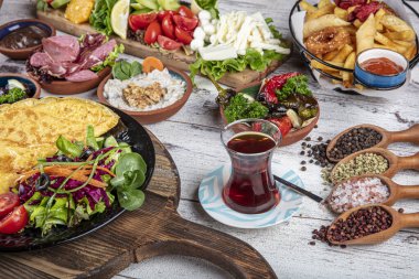Türk kahvaltı masası. Hamur işleri, sebzeler, yeşiller, zeytinler, peynirler, omlet, baharatlar, reçeller, bal, termosta çay, büyük bir kompozisyon. Restoranda ve kafede kahvaltı konsepti.