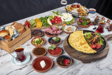 Türk kahvaltı masası. Hamur işleri, sebzeler, yeşiller, zeytinler, peynirler, omlet, baharatlar, reçeller, bal, termosta çay, büyük bir kompozisyon. Restoranda ve kafede kahvaltı konsepti.