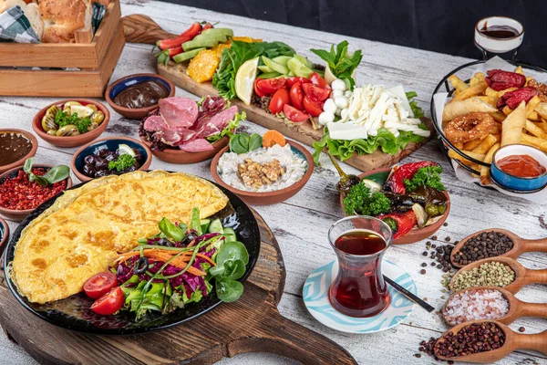 Türk kahvaltı masası. Hamur işleri, sebzeler, yeşiller, zeytinler, peynirler, omlet, baharatlar, reçeller, bal, termosta çay, büyük bir kompozisyon. Restoranda ve kafede kahvaltı konsepti.