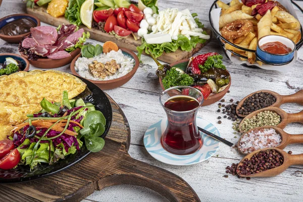 Türk kahvaltı masası. Hamur işleri, sebzeler, yeşiller, zeytinler, peynirler, omlet, baharatlar, reçeller, bal, termosta çay, büyük bir kompozisyon. Restoranda ve kafede kahvaltı konsepti.