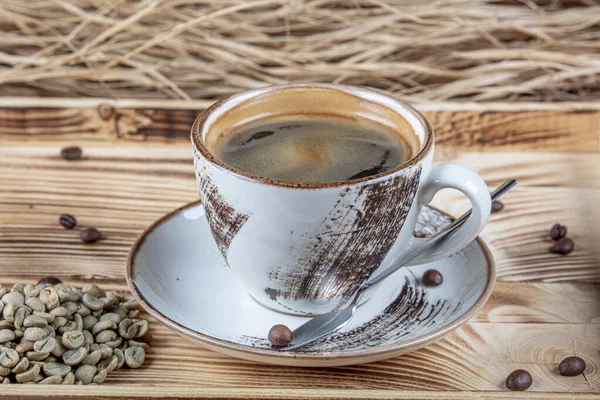 コーヒーカップにホットコーヒーと多くのコーヒー豆は コピースペースと 暗い背景に 暖かくて軽い雰囲気の木製のテーブルの上に それの周りに配置されています — ストック写真