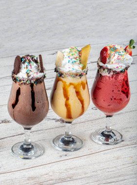 Üç bardak çeşitli aromalı milkshake. Çikolata, ananas ve çilekli milkshake..