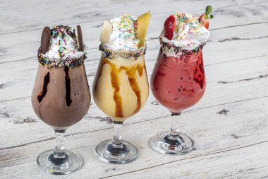 Üç bardak çeşitli aromalı milkshake. Çikolata, ananas ve çilekli milkshake..