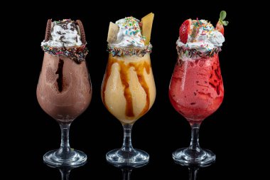 Üç bardak çeşitli aromalı milkshake. Çikolata, ananas ve çilekli milkshake..