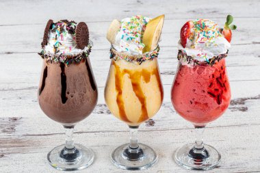 Üç bardak çeşitli aromalı milkshake. Çikolata, ananas ve çilekli milkshake..