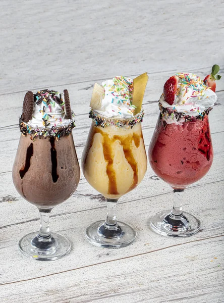 Üç bardak çeşitli aromalı milkshake. Çikolata, ananas ve çilekli milkshake..