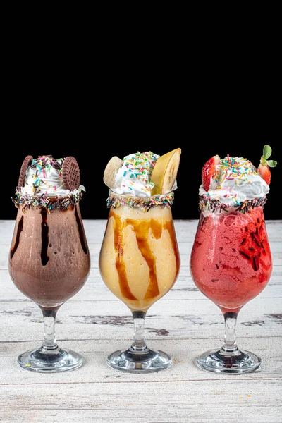 Üç bardak çeşitli aromalı milkshake. Çikolata, ananas ve çilekli milkshake..