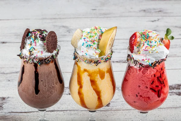 Üç bardak çeşitli aromalı milkshake. Çikolata, ananas ve çilekli milkshake..