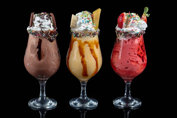 Üç bardak çeşitli aromalı milkshake. Çikolata, ananas ve çilekli milkshake..