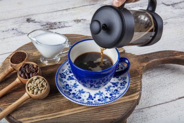 Kahve filtresi. Kahveyi fincana doldurmanın buharı, bir fincan taze kahve. Bir fincan kahve ile bir kahve çekirdeği serpintisi. Tahta sunum, sıcak yemek ve sağlıklı yemek konsepti..