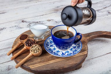 Kahve filtresi. Kahveyi fincana doldurmanın buharı, bir fincan taze kahve. Bir fincan kahve ile bir kahve çekirdeği serpintisi. Tahta sunum, sıcak yemek ve sağlıklı yemek konsepti..