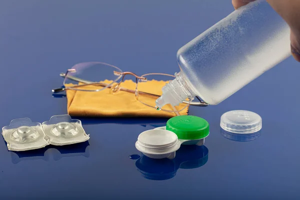 Eye glasses and contact lenses. Glasses, containers and contact lenses, isolated on blue background.