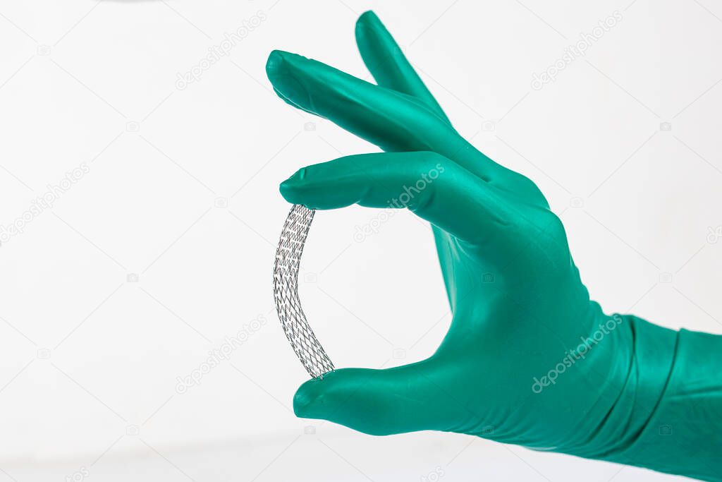 Stent and catheter for implantation into blood vessels with an empty and filled balloon. Metal stent for implantation and supporting blood circulation into blood vessels. Stent in doctor's hand.