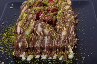 Belgian waffles decorated with chocolate sauce and fresh fruits isolated on black background.