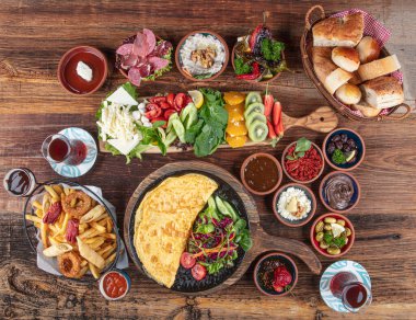 Traditional Turkish Breakfast served with traditional turkish tea on wood table. Breakfast or brunch table filled with all sorts of delicious delicatessen. Turkish name; Serpme Kahvalti.