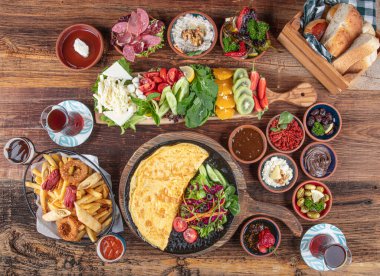 Traditional Turkish Breakfast served with traditional turkish tea on wood table. Breakfast or brunch table filled with all sorts of delicious delicatessen. Turkish name; Serpme Kahvalti.