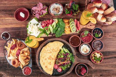 Traditional Turkish Breakfast served with traditional turkish tea on wood table. Breakfast or brunch table filled with all sorts of delicious delicatessen. Turkish name; Serpme Kahvalti.
