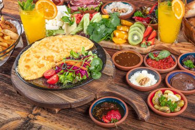 Traditional Turkish Breakfast served with traditional turkish tea on wood table. Breakfast or brunch table filled with all sorts of delicious delicatessen. Turkish name; Serpme Kahvalti.